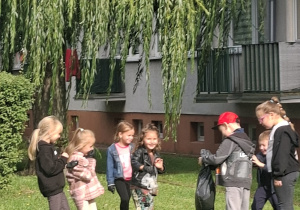 Dzieci na trawniku zbierają śmieci
