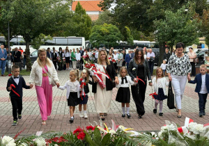Dzieci wraz z nauczycielami podchodzą do pomnika