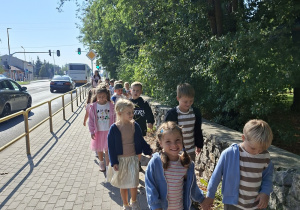 dzieci idą po chodniku obok ulicy