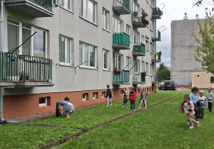 Dzieci zbierają śmieci na trawniku obok bloku