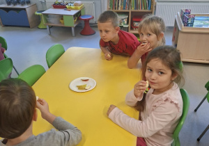 Dzieci jedzą jabłka przy stoliku