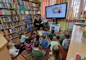 Dzieci siedzą na dywanie słuchają bajki o czarownicy