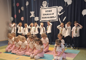 Dziewczynki siedzą a chłopcy podnoszą ręce do góry