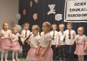 Dwie dziewczynki śpiewają piosenkę w tle pozostała grupa