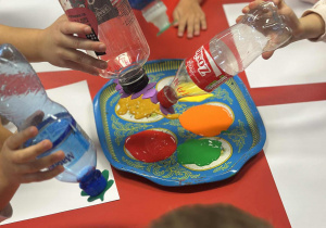 Dzieci moczą butelki w farbie kolorowej