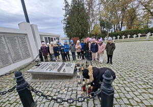 Chłopiec kładzie symbloczny znicz na grobie