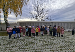 Grupa "Wiewiórek" stoi na tle pamiątkowej tablicy