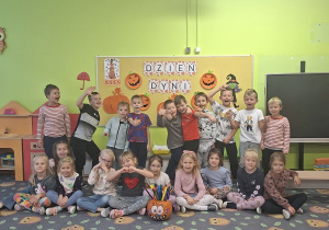 Dzieci stoją na tle dekoracji związanej z dniem dyni