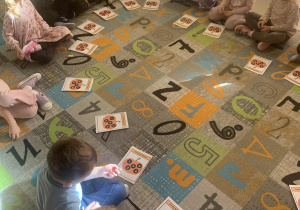 Dzieci w kole bawią się w zabawę matematyczną z dyniami