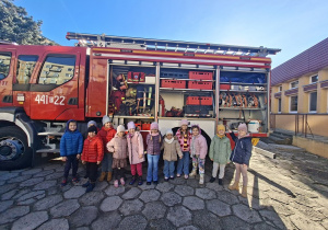 Dzeci z grupy "Sowy" stoją przed wozem strażackim