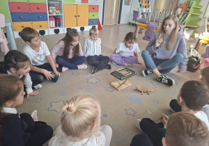 Dzieci siedzą w kole i oglądają kameleona