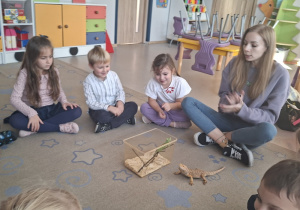 Dzieci siedzą w kole i słuchają ciekawostek nt. życia kameleona