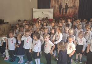 Dzieci w pozycji stojącej śpiewają hymn