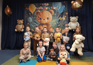 Grupa "Rybki" stoi ze swoimi misiami na tle dekoracji