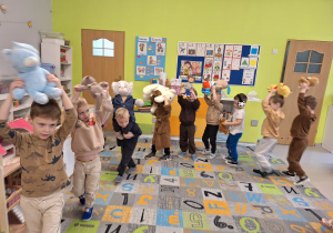 Dzieci maszerują trzymając misia nad głową