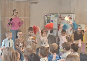 Kilkoro dzieci razem z prowadzącymi tańczy i gra do muzyki