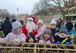 Kilkoro dzieci siedzi w saniach ze Św. Mikołajem