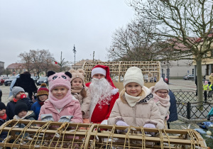 Kilkoro dzieci siedzi w saniach ze Św. Mikołajem