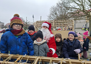 Kilkoro dzieci siedzi w saniach ze Św. Mikołajem