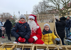 Kilkoro dzieci siedzi w saniach ze Św. Mikołajem