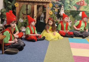 Krasnoludki ze Śnieżką siedzą wokół domku