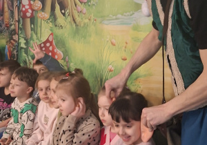 Krasnoludek przymierza uszy dziewczynce