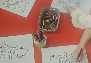 Dzieci kolorują obrazek z dinozaurem