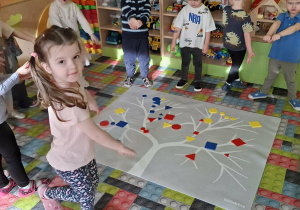 Dzieci stoją wokół drzewka z figurami