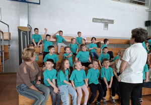 Dzieci siedzą na ławkach na widowni