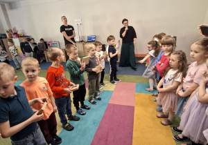 Grupa chłopców stoi z prezentami na przeciwko dziewczynek