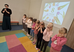 Dziewczynki stoją z zasłoniętymi oczami