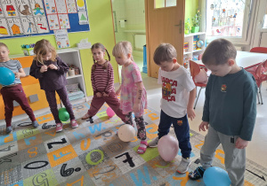 Dzieci trzymają balony między nogami