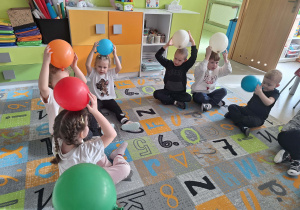 Dzieci trzymają balony nad głową