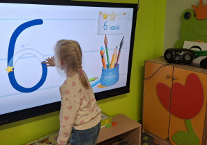 Dziewczynka rysuje na monitorze cyfrę 6