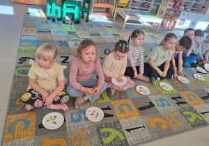 Dzieci na dywanie z talerzykami z warzywami