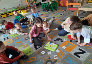 Dzieci przeliczają liczmany na dywanie