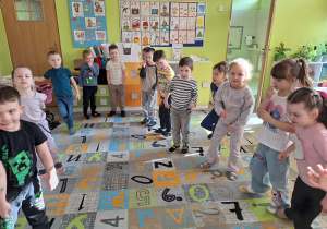 Dzieci wykonują polecenia ruchowe na dywanie