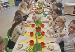 Dzieci siedzą przy wielkanocnym stole