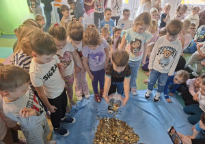 Dzieci usypują górę z zebranych monet