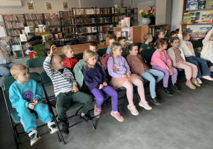 Dzieci siedzą na krzesełkach i słuchają ciekawostek o zwierzętach