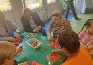 Dzieci przy stoliku wraz ze swoimi dziadkami przeliczają liczmany