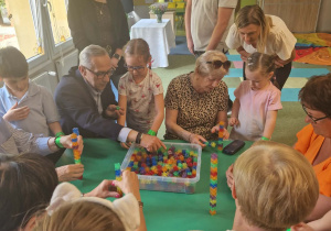 Dzieci przy stoliku wraz ze swoimi dziadkami budują wieże z klocków