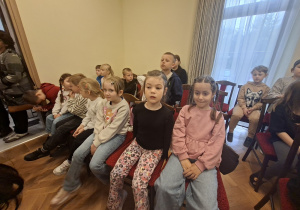 Dzieci siedzą i oglądają koncert uczniów szkoły