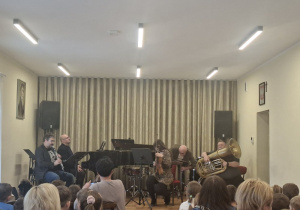 Nauczyciele szkoły grają na scenie na różnych instrumentach