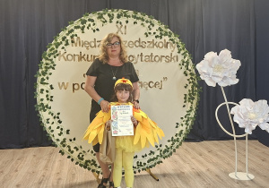 Dziewczynka stoi z dyplomem razem z p.dyrektor