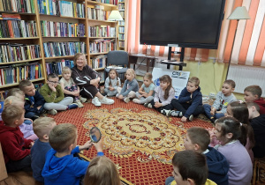 Dzieci siedzą w kole razem z Panią z biblioteki