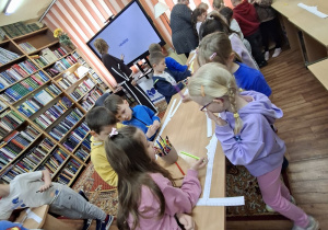 Dzieci przy stolikach kolorują korony