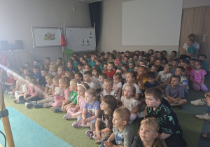 Dzieci siedzą na dywanie i oglądają przedstawienie