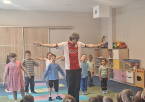 Grupa dzieci tańczy razem z prowadzącym elementy tańca break dance