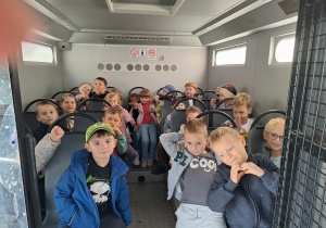 Dzieci siedzą w środku pojazdu wojskowego